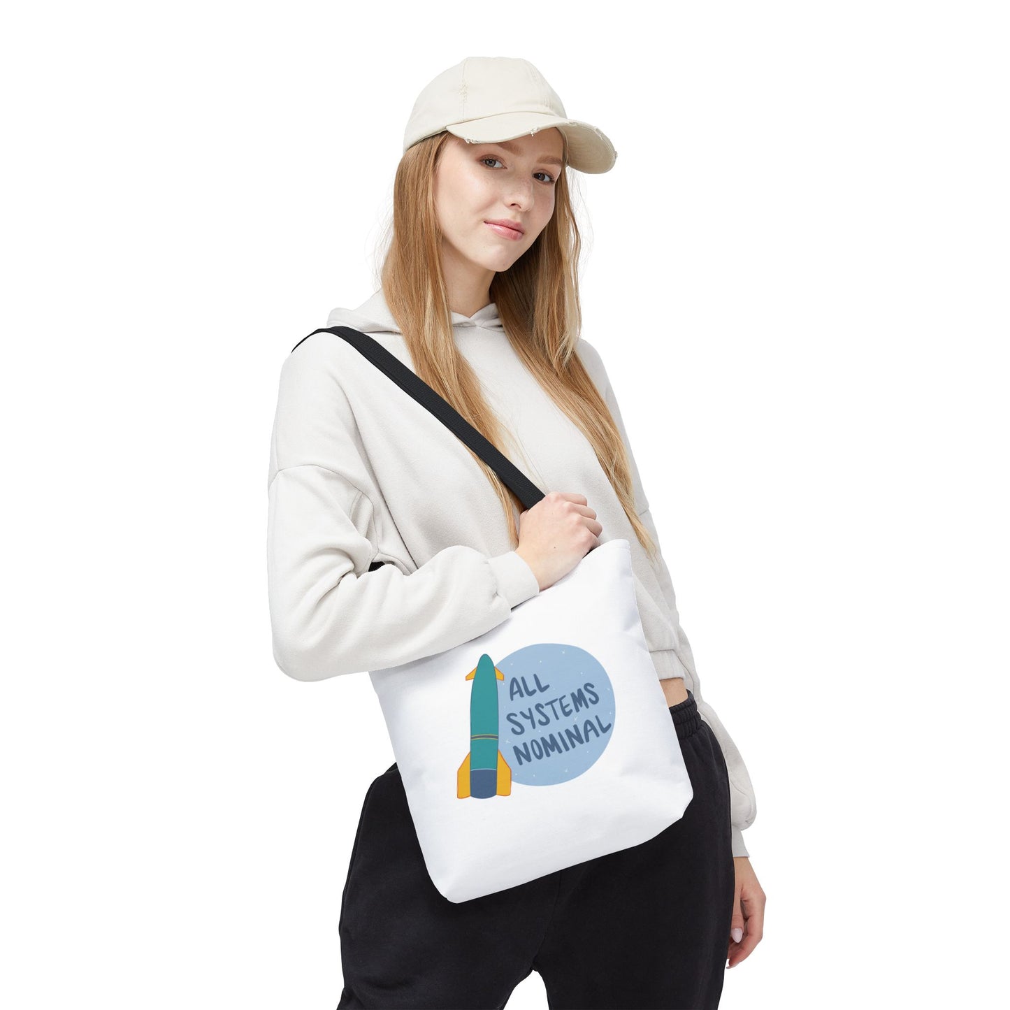 Person wearing a white cap and holding a white tote bag with a colorful design and text.